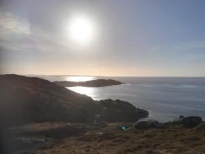 a sun setting over the ocean on a cliff at Achmelvich View self catering in Lochinver