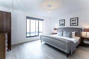 a bedroom with a bed and a large window at City Aldgate Apartments in London
