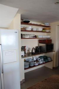 a kitchen with a white refrigerator and shelves with dishes at 43 Artemis in Langebaan