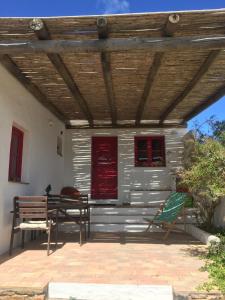 eine Terrasse mit einem Tisch und Stühlen unter einem Holzdach in der Unterkunft Casa Pedralva in Vila do Bispo