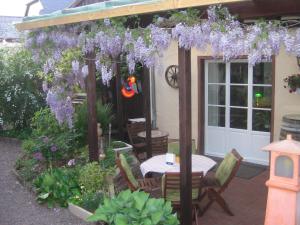 un patio con mesa y glicinas púrpuras en Ferienwohnungen Bistro Tebecks en Wadern