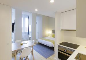 a bedroom with a bed and a table and a kitchen at Mercado dos Poetas – Tourism Apartments in Porto