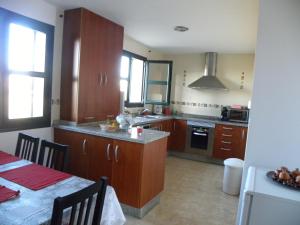 una cocina con armarios de madera y una mesa con sidra de mesa en El Jardin de los Gatos Apartament, en Cáceres