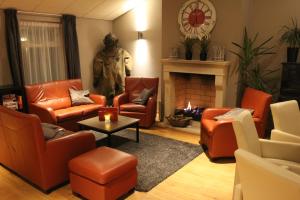 a living room with orange chairs and a fireplace at Hotel Restaurant 't Klokje in Renesse