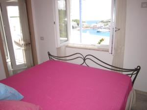 uma cama rosa num quarto com uma janela em L'ANGOLO DEI ROMANTICI em Ponza