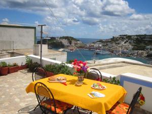 einen gelben Tisch und Stühle auf einem Balkon mit Aussicht in der Unterkunft L'ANGOLO DEI ROMANTICI in Ponza