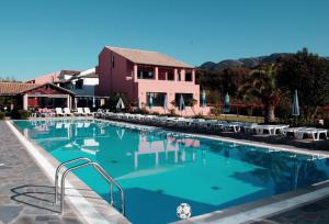 a large swimming pool with chairs and a building at Nireas Resort Corfu in Acharavi
