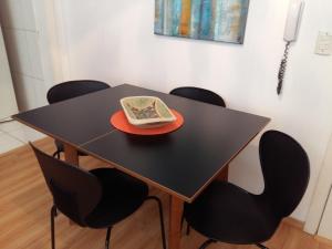 una mesa negra con sillas y un plato con un libro. en Apartamento Lago Grande Hotel, en Canela