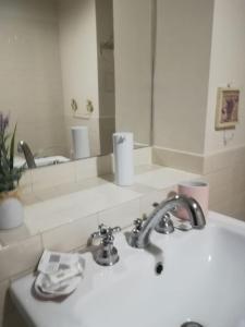 een wastafel in de badkamer met een kraan en een spiegel bij At Home Lettieri in Napels