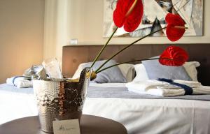un vaso con fiori rossi su un tavolo accanto a un letto di I Segreti della Valle a Agrigento