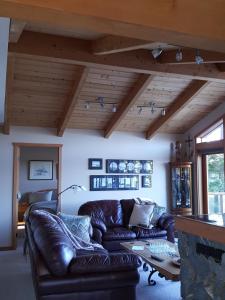un soggiorno con divano in pelle e camino di Reef Point Oceanfront Bed and Breakfast a Ucluelet