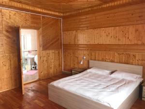 ein Schlafzimmer mit einem Bett in einer Holzwand in der Unterkunft Котедж "Relax" in Mykulytschyn