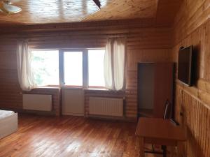 Zimmer mit einem großen Fenster und Holzboden in der Unterkunft Котедж "Relax" in Mykulytschyn