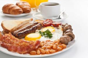 a plate of breakfast food with eggs bacon beans and a cup of coffee at Nireas Studios & Aparts in Acharavi
