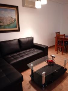 Sala de estar con sofá de cuero negro y mesa de centro en Real, en Toledo