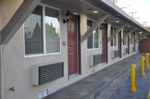 uma fila de janelas num edifício com uma porta vermelha em Sun Light Motel em Downey