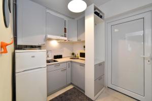 a small kitchen with white cabinets and a door at Block Apartment Upper Town in Zagreb
