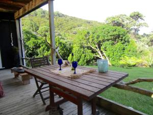 - une table en bois avec 3 verres à vin sur une terrasse couverte dans l'établissement Mulberry Grove Retreat, à Tryphena