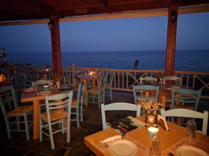a restaurant with tables and chairs and the ocean at Gigilos in Agia Roumeli