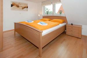 um quarto com uma cama grande com lençóis laranja em Haus Benser Riff em Bensersiel