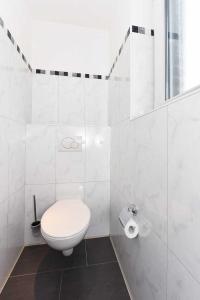 uma casa de banho branca com um WC e 2 rolos de papel higiénico em Haus Benser Riff em Bensersiel