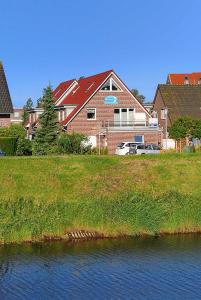 a large house next to a body of water at Ferienwohnungen Am Sieltor in Bensersiel