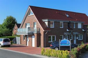 a brick house with a van parked in front of it at Ferienwohnungen Am Kajedeich in Bensersiel