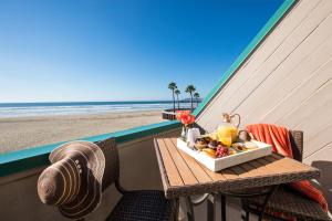 - une table avec un plateau de nourriture sur le balcon donnant sur la plage dans l'établissement SeaVenture Beach Hotel, à Pismo Beach