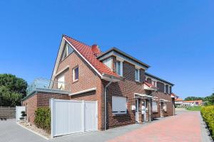 a brick house with a white fence on a street at Ferienwohnungen Am Sieltor in Bensersiel