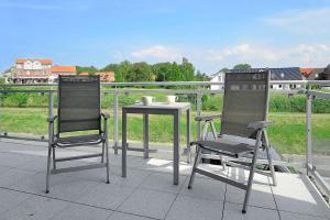 two chairs and a table on a balcony at Ferienwohnungen Am Kajedeich in Bensersiel