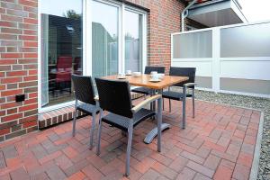 a wooden table and chairs on a patio at Ferienwohnungen Am Kajedeich in Bensersiel
