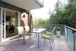 d'une terrasse avec une table et des chaises sur un balcon. dans l'établissement Nordseegartenpark Terrassien, à Bensersiel