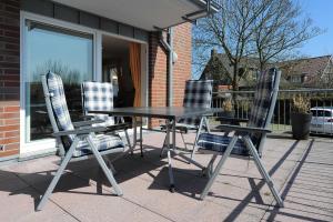 une table et quatre chaises sur la terrasse dans l'établissement Nordseegartenpark Terrassien, à Bensersiel