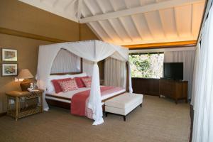 1 dormitorio con cama con dosel y TV en Pousada Tutabel en Trancoso