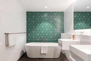 a bathroom with a tub and a green wall at Citadines Connect Sydney Airport in Sydney