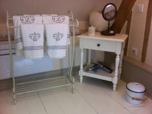 a bathroom with white towels and a table with a mirror at La Charmée in Jonquières