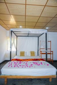 a bedroom with a bed with pink flowers on it at Walampuri Cabana & Restaurant in Tangalle