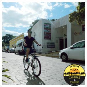a man riding a bike down a street at Cabañas Camping Ria Celestun in Celestún