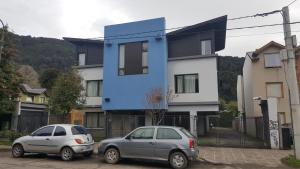 dos autos estacionados en un estacionamiento frente a una casa en Moderno Departamento Centro en San Martín de los Andes