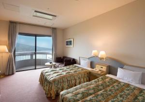 a hotel room with two beds and a balcony at Izumigo Hotel Altia Toba in Toba