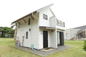 a white house with a door on the side of it at Rest and Lodge Syou in Amami