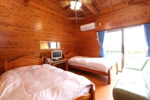 a bedroom with two beds and a television in a cabin at Rest and Lodge Syou in Amami