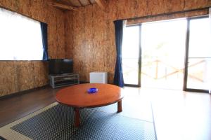 a living room with a wooden table and a television at Rest and Lodge Syou in Amami