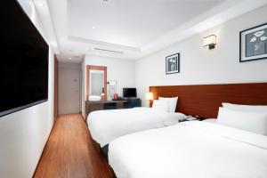 釜山にあるライオン ホテルのベッド2台、薄型テレビが備わるホテルルームです。