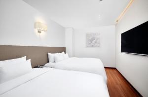ein Hotelzimmer mit 2 Betten und einem Flachbild-TV in der Unterkunft Lion Hotel in Busan