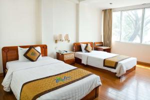 a hotel room with two beds and a window at Bamboo Green Riverside Hotel in Danang