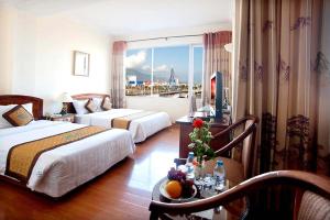 a hotel room with two beds and a table with fruits on it at Bamboo Green Riverside Hotel in Danang
