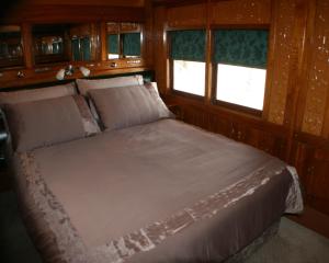 uma cama num quarto com paredes e janelas de madeira em Carriages Spa Retreat em Echuca