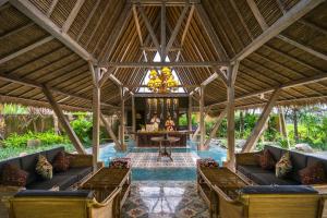 an outdoor pavilion with couches and a table and a chandelier at Arya Villas Ubud in Ubud