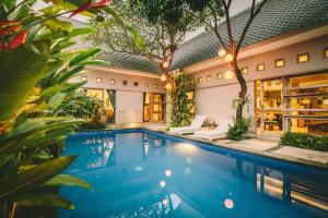 a swimming pool in front of a house with plants at Lokal Bali Hostel in Kuta